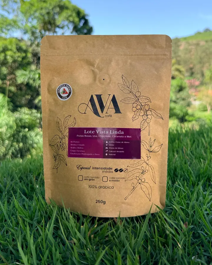 Pacote de 250 g do Lote Vista Linda AVA café sobre a grama, com a lavoura ao fundo